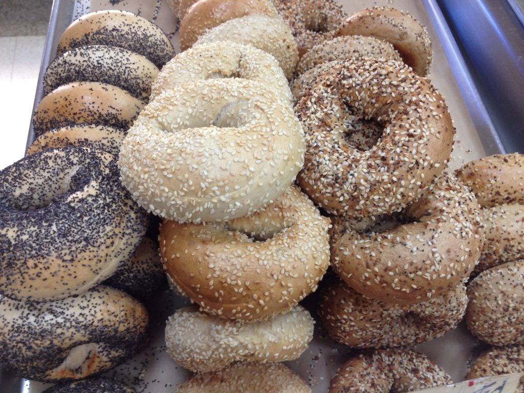 Close-up view of assorted organic bagels with sesame, poppy seed, and multi-grain toppings from Little Shop of Bagels.